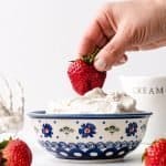 Dipping a strawberry into a bowl of homemade vanilla whipped cream