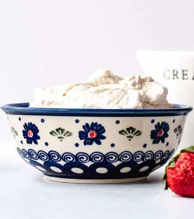 Vanilla Whipped Cream in an ornate blue bowl with strawberry on the side