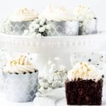 Chocolate Sour Cream Fudge Cupcakes, single cupcake on plate cut in half with cupcakes on cake stand behind and flowers | kickassbaker.com