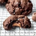 Salted Caramel Stuffed Dark Chocolate Cookies close up of bitten cookie with caramel spilling out of center | kickassbaker.com