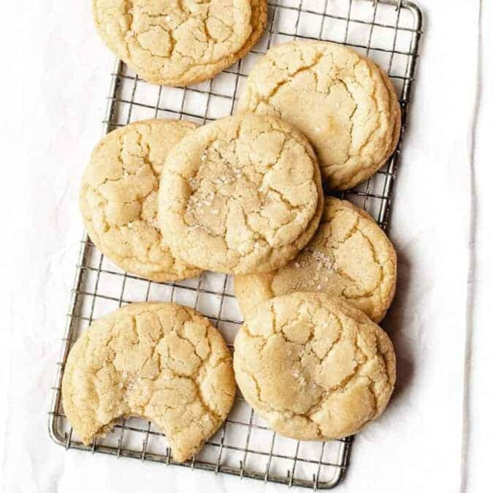 Soft and chewy no-chill sugar cookies on a cooling rack with a bite taken out of one.