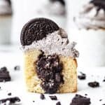 Oreo Cupcakes Stuffed with Chocolate Ganache cut in half to see the filling, Oreo cookie crumbles scattered around