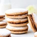 Alfajore sandwich cookies close up of 3 cookies stacked and one leaning against the stack