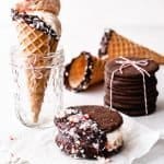 White Chocolate Peppermint Ice Cream in a waffle cone, in an ice cream sandwich, chocolate wafer cookies stacked behind with two waffle cones in background