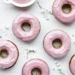 Overhead shot of baked donuts with pink ruby chocolate glaze and white flowers spread across