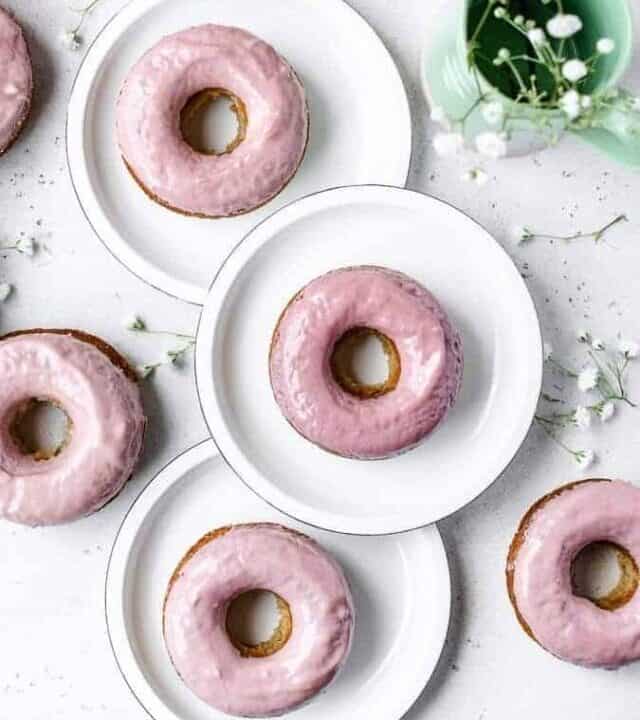 Overhead shot of baked donuts on plates with pink chocolate glaze