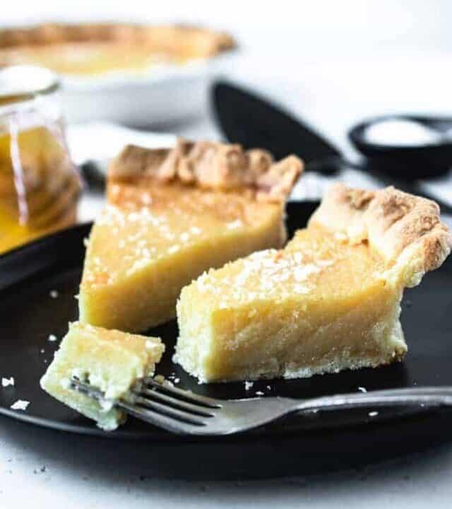 2 slices of salted honey pie on a black plate with a bite taken out of one