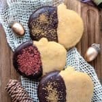 Overhead photo of 3 pumpkin sugar cookies dipped in chocolate with sprinkles