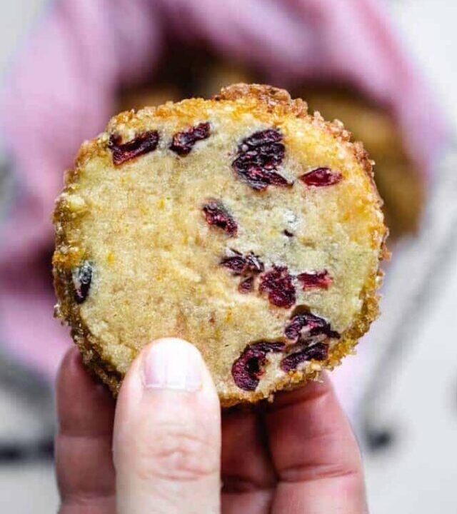 close-up photo of orange cranberry shortbread cookie being held in the air