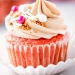 Close up of pink champagne cupcake with white chocolate buttercream and sprinkles