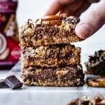stack of 3 sweet and salty cereal snack bars with hand reaching for top one