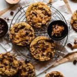 milk chocolate chip toffee cookies on a round cooling rack with ingredients around it
