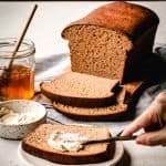 spreading butter on a slice of honey wheat bread