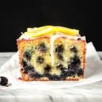 lemon blueberry loaf cake sliced with glaze dripping down the front
