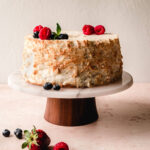 Angel food cake on a cake stand with fresh berries garnished on top.