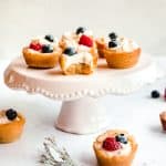 sugar cookie fruit tarts on a cake stand with bite taken out