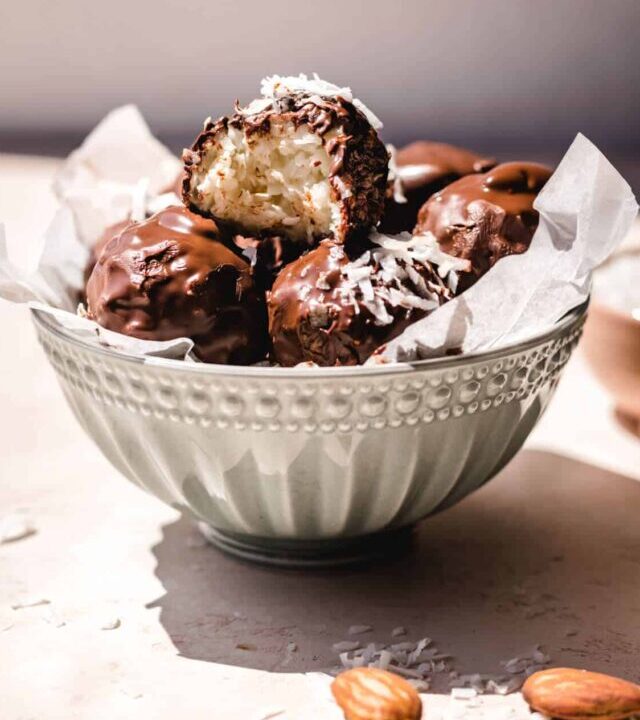 A bowl full of chocolate covered no bake coconut balls with condensed milk