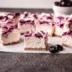 Squares of no bake cherry cheesecake with whole cherries.