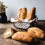 Vietnamese bread rolls in a basket and on the counter in front of them.