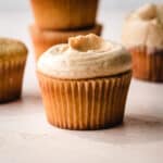 Frosted vanilla cupcake sitting in front of other cupcakes.