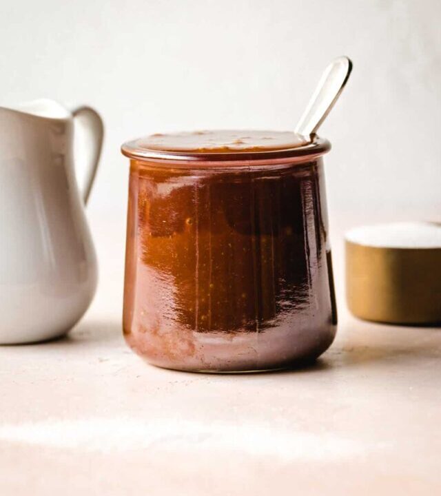 Salted caramel in a glass jar with a spoon inside.