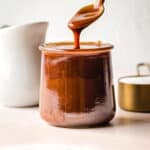 Spoon drizzling salted caramel into a small glass container.