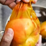 Hand pulling off the skin of a peach.