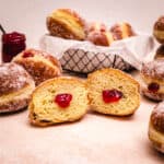 Half of a Hanukkah jelly donut revealing the strawberry jelly inside.