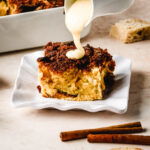 Bourbon sauce being poured over a slice of bread pudding.