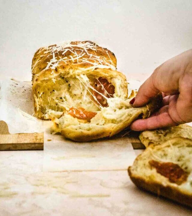 Hand pulling away freshly baked pull apart pizza dough.