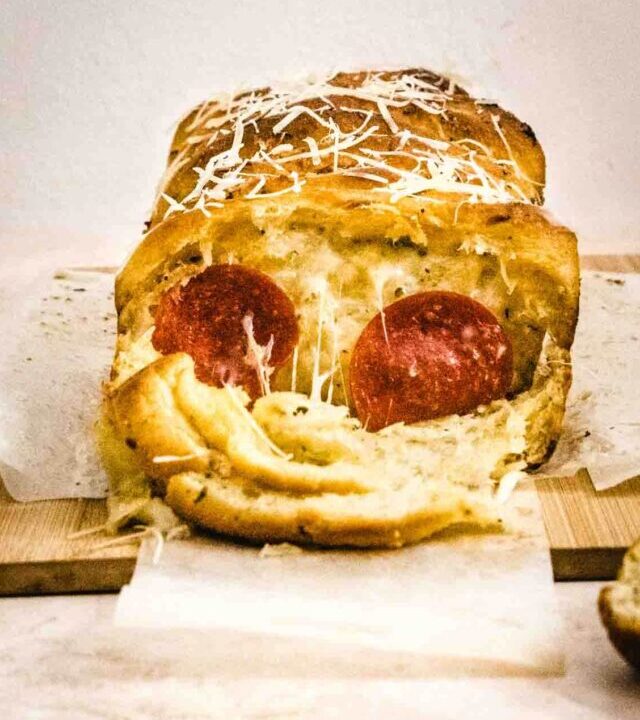 side view of baked pull apart pizza showing melted cheese and pepperoni slices.