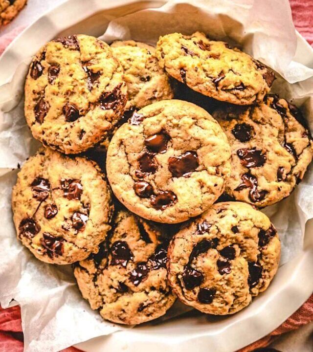 Vegan chocolate chip oatmeal cookies laying on parchment paper in a pie plate.