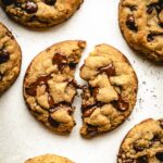 Melted chocolate chips oozing out of a broken in half vegan chocolate chip oatmeal cookie.