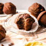 Large coffee muffin with a big bite taken out of it sitting on top of a paper muffin liner.