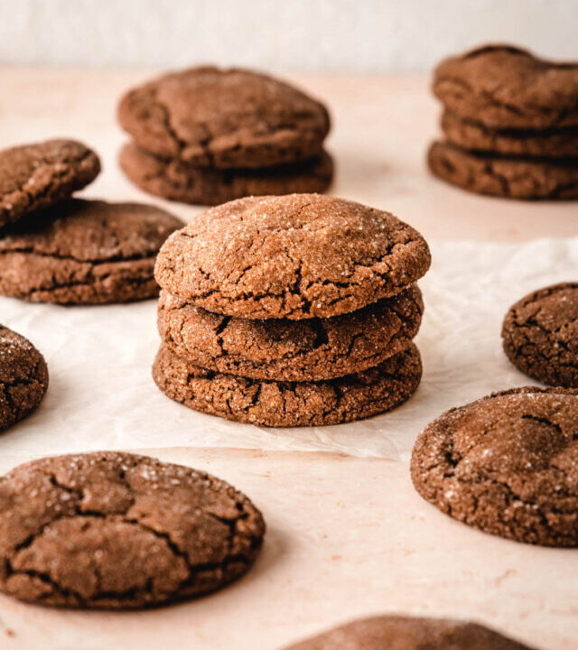 Stacks of chocolate sugar cookies and some scattered around them.