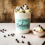 Ice cream container with vanilla malted ice cream with chocolate chips with a bowl of ice cream next to it.