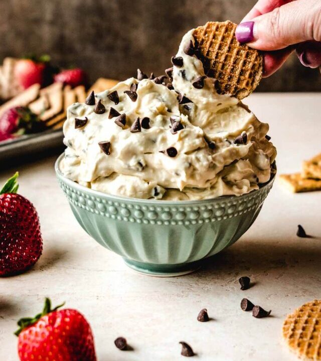 Hand dipping a waffle cracker into a bowl of quick whipped chocolate chip dip with cream cheese.