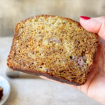 Hand holding a slice of moist banana bread made with oil.