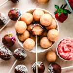 Cake pops in a dish with one in the center with a bite taken out.