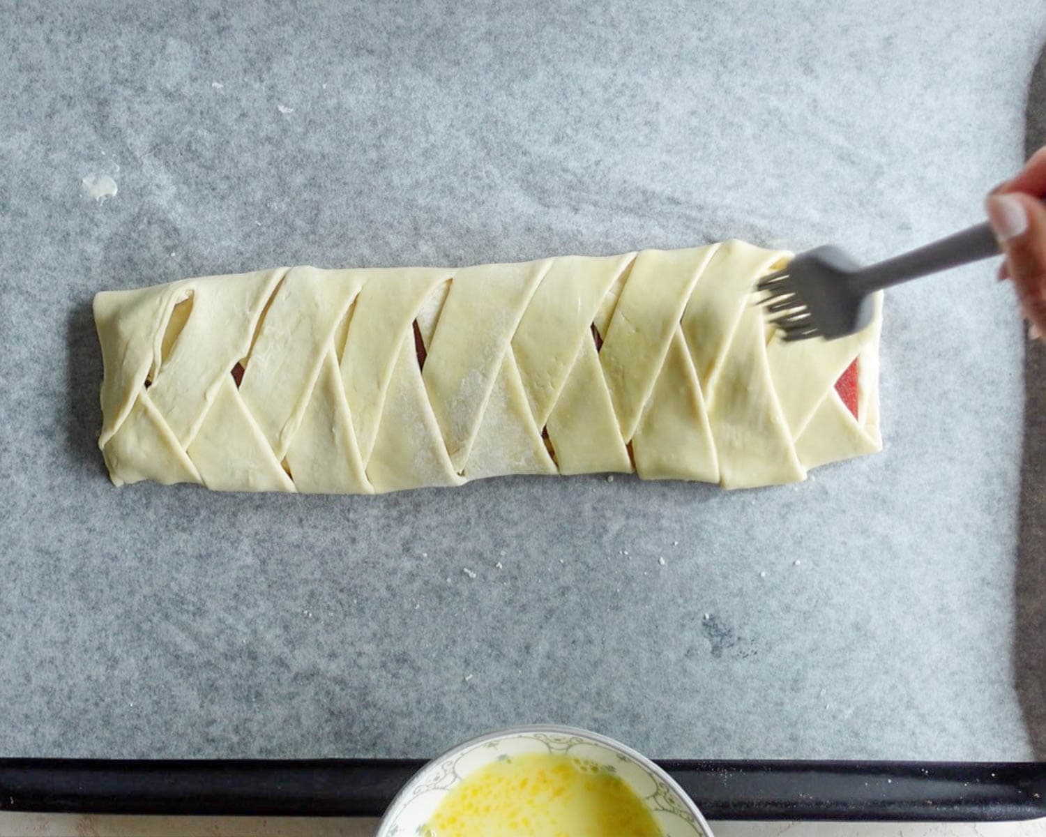 Brush egg wash on top of braided puff pastry.